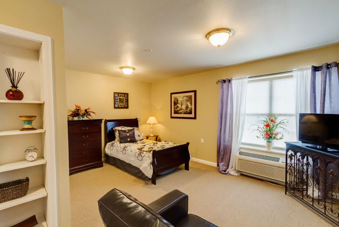 A cozy bedroom with a bed, dresser, and window adorned with curtains and decor.