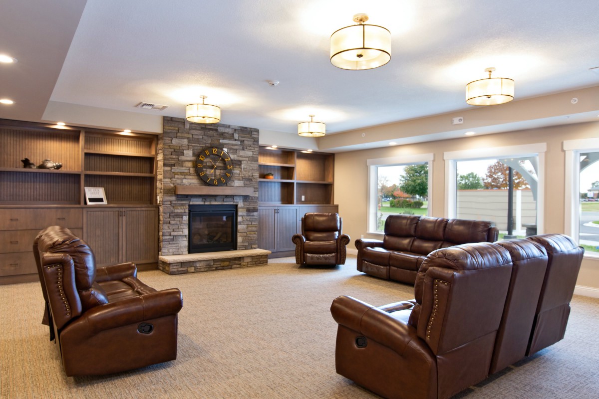 A cozy living room featuring leather seating and a stone fireplace.