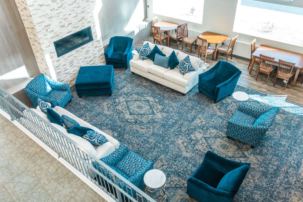 A stylish living room with blue chairs, a white sofa, and a patterned carpet.