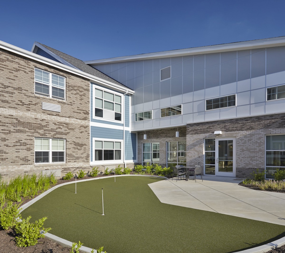 A modern building with a small landscaped outdoor area featuring artificial grass.