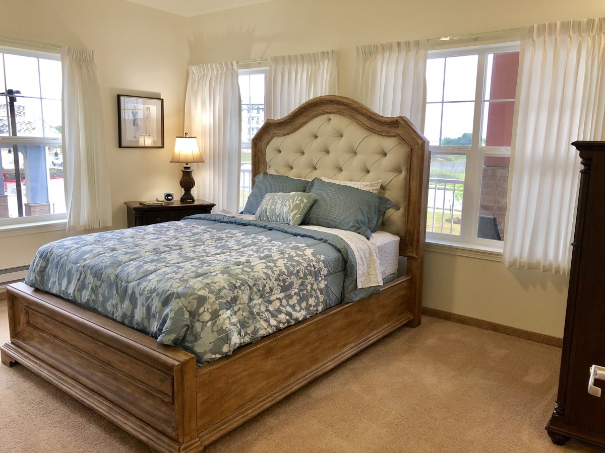 A cozy bedroom with a wooden bed frame, plush headboard, and elegant decor.
