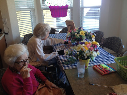 A group of seniors enjoying a leisurely activity together at a decorated table.