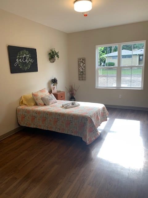 A minimalist bedroom with a single bed and sunlight streaming through the window.