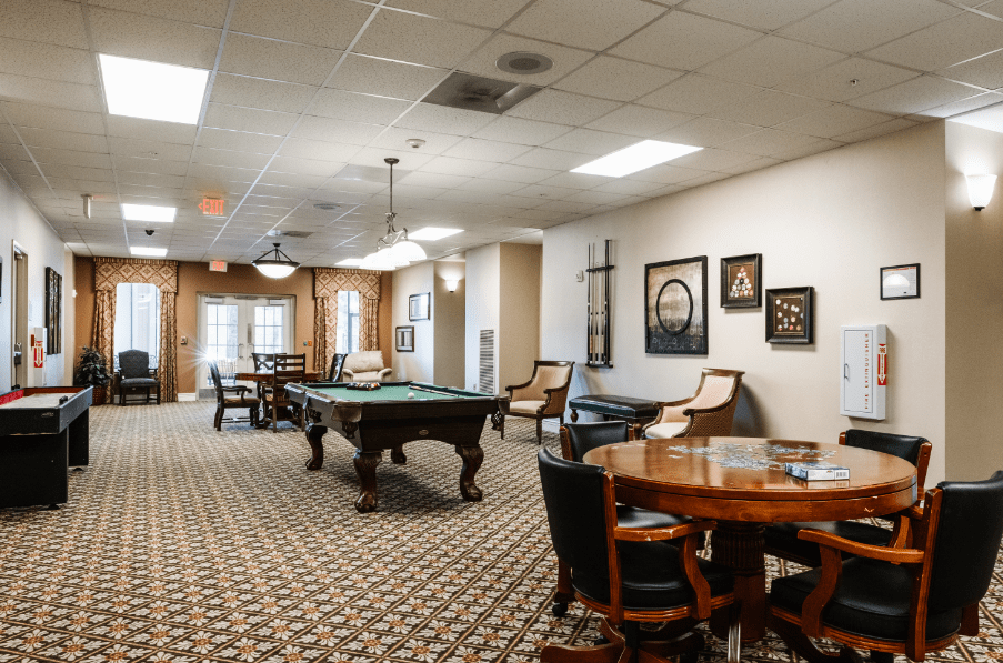 A spacious game room featuring a pool table, comfortable seating, and decorated walls.