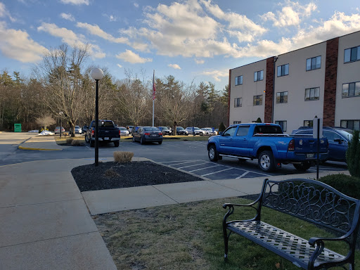 A view of a parking lot with a blue truck, surrounded by buildings and a cloudy sky.