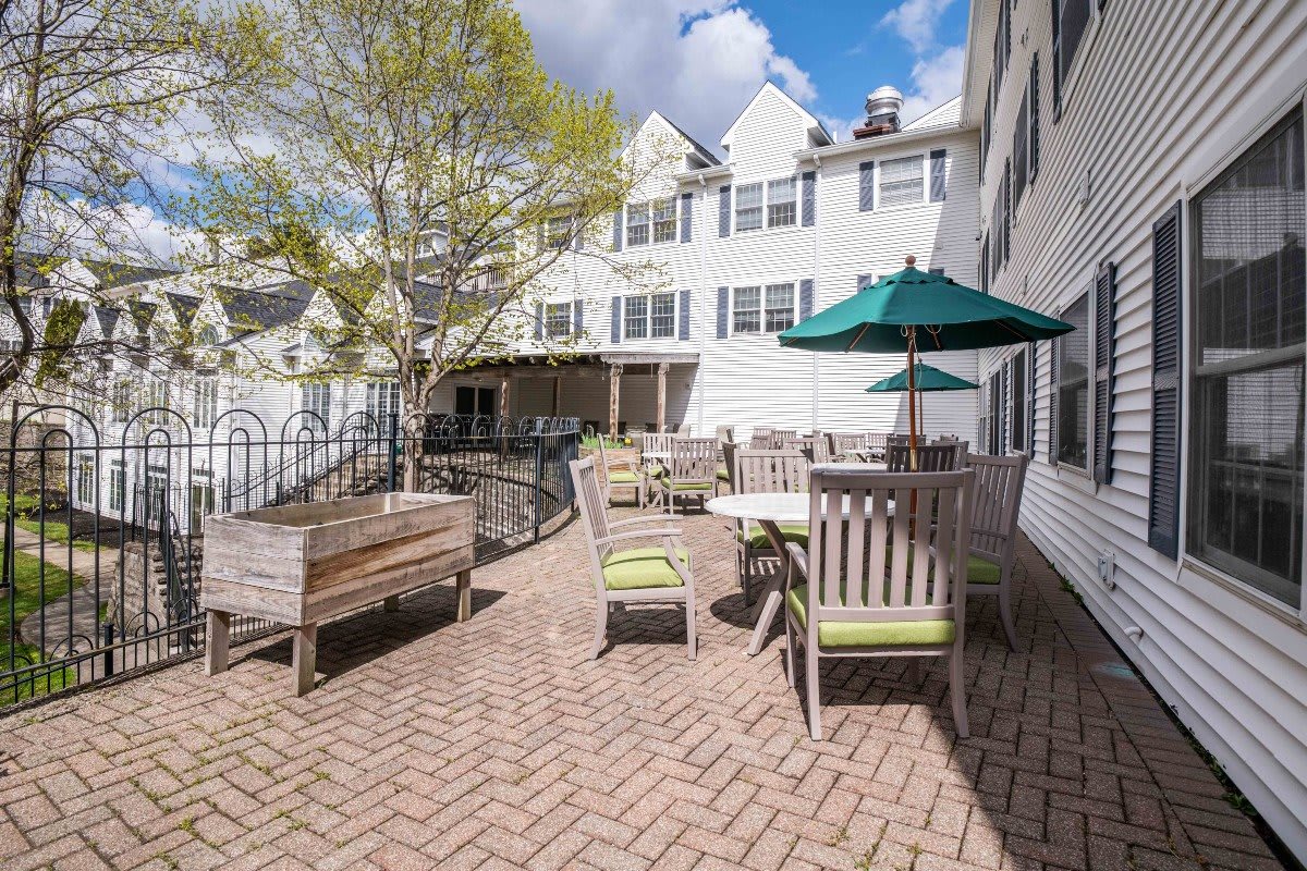 A sunny patio area with outdoor seating and umbrellas beside a white building.