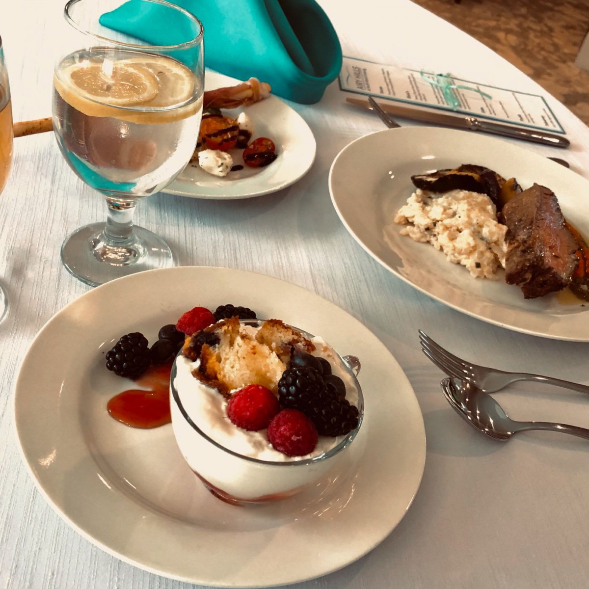 A table set with a dessert topped with berries, a savory dish, and a cappuccino.