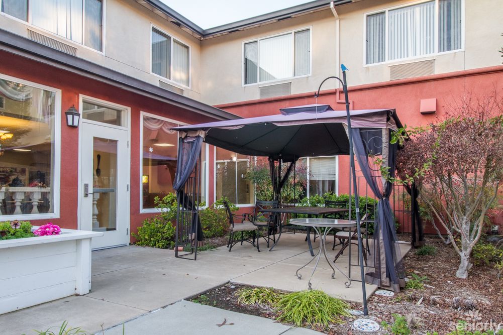 A cozy outdoor patio area with a canopy and seating surrounded by a building.