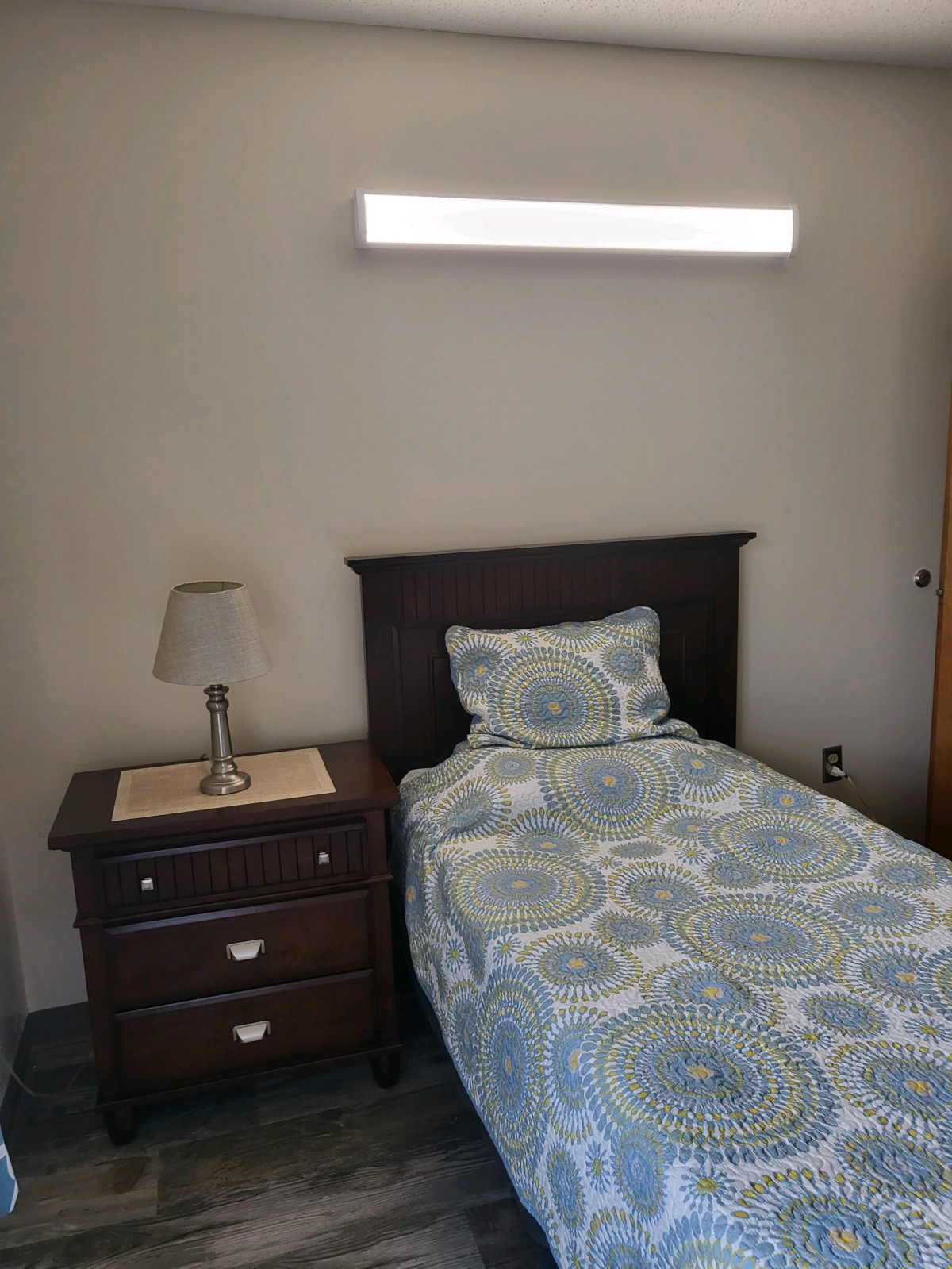 A simple bedroom with a single bed and nightstand.