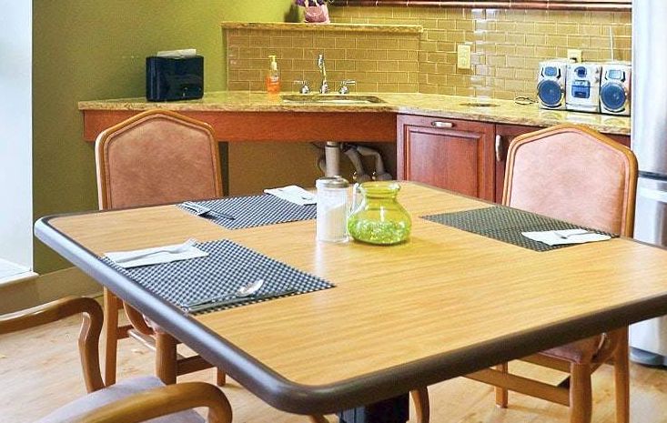 A cozy kitchen space with a dining table set for four, featuring placemats and a decorative glass jar.