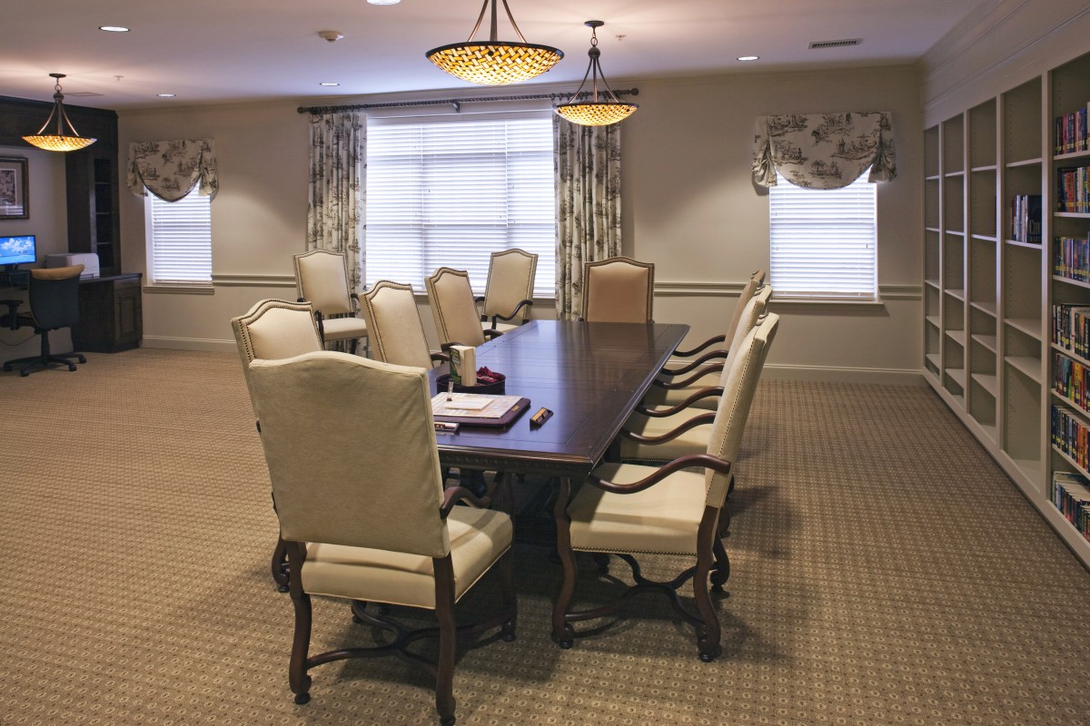 A well-furnished conference room with a large meeting table surrounded by chairs.