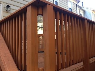 A wooden deck with vertical railings attached to a house.