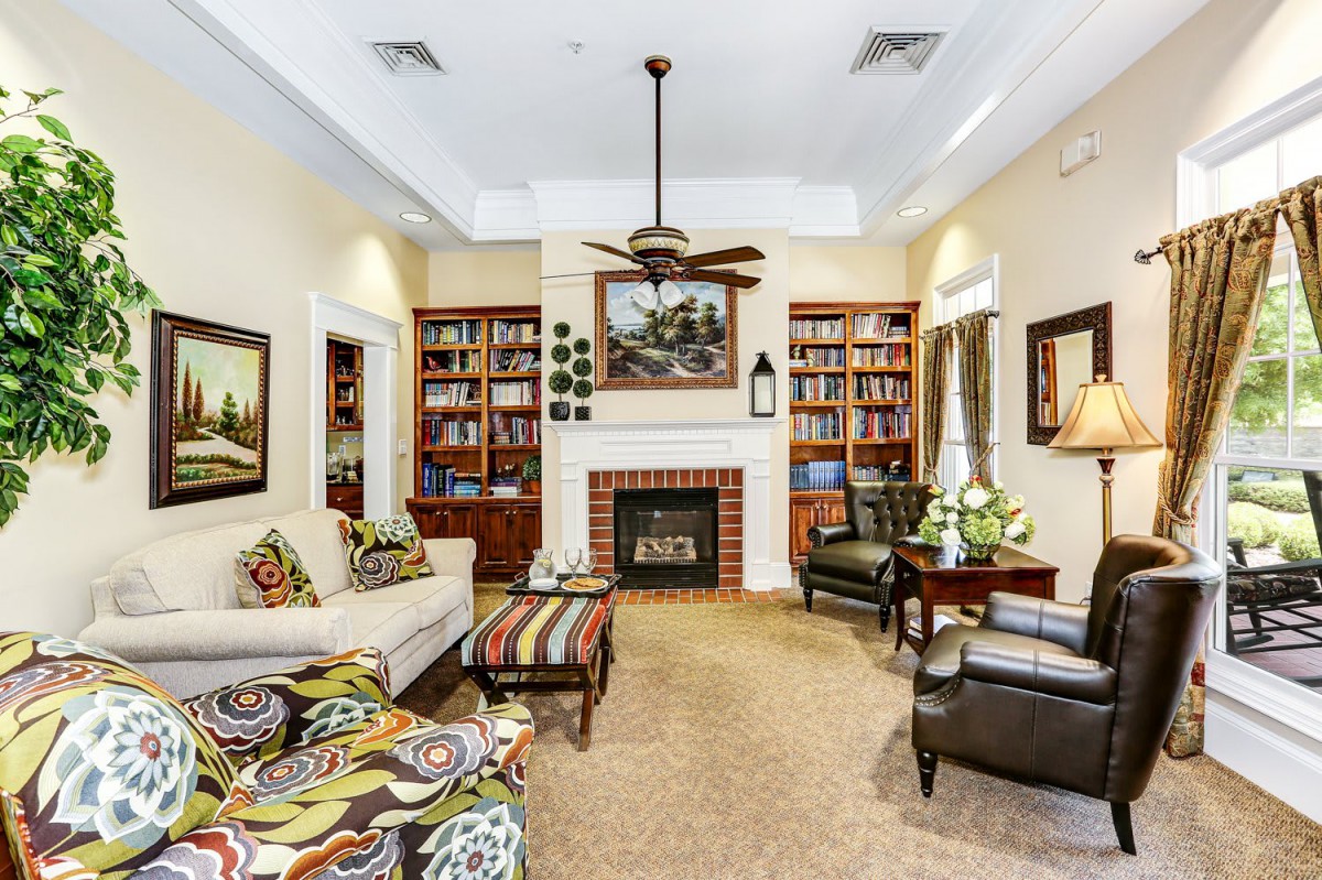 A cozy living room with a fireplace, surrounded by bookshelves and comfortable seating.