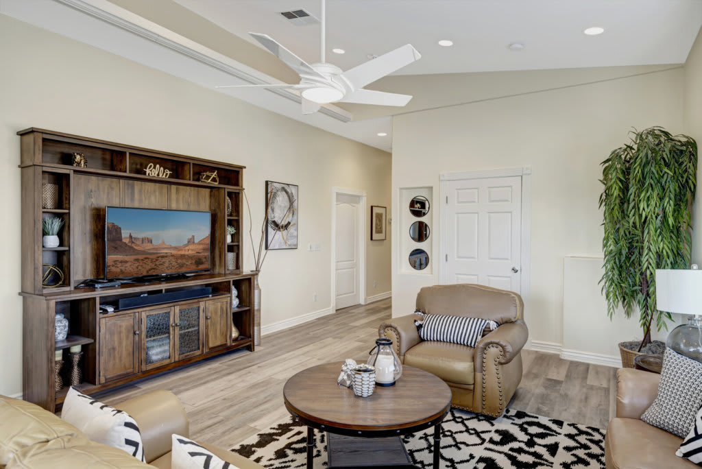 A modern living room featuring a large TV cabinet, comfortable armchair, and a stylish coffee table with decorative items.
