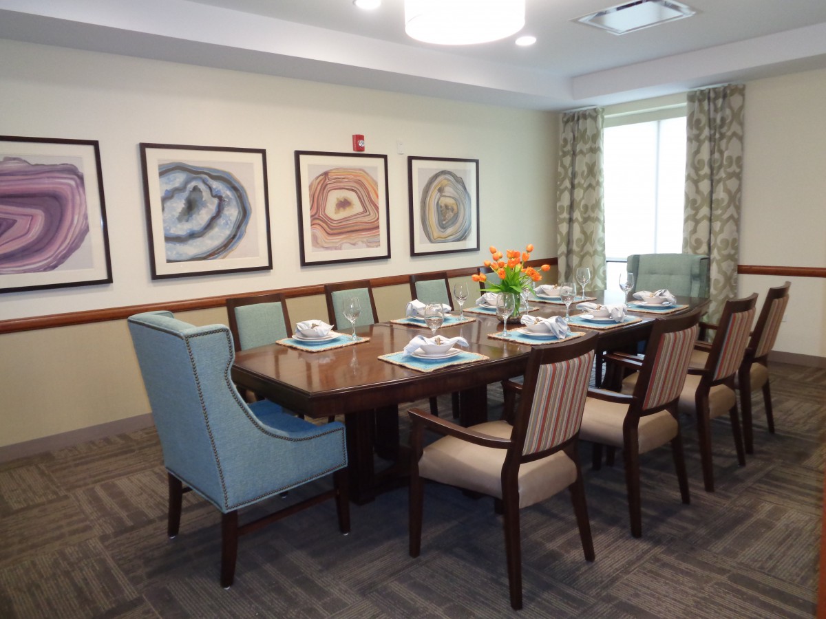 A formal dining room setup with a large table, chairs, and decorative artwork on the walls.