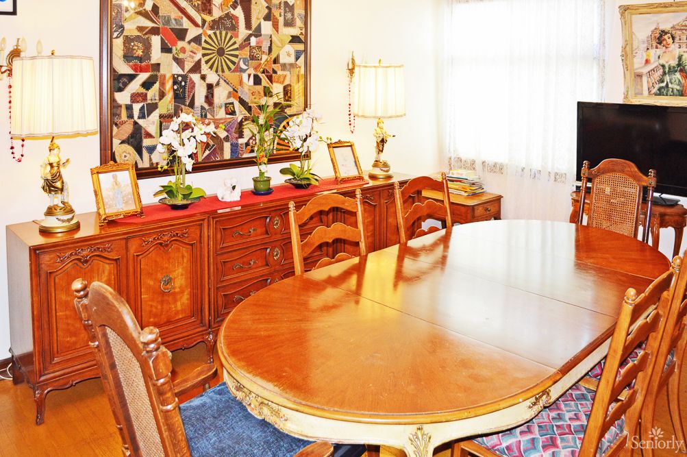 A cozy dining room with elegant wooden furniture and decorative quilt art on the wall.