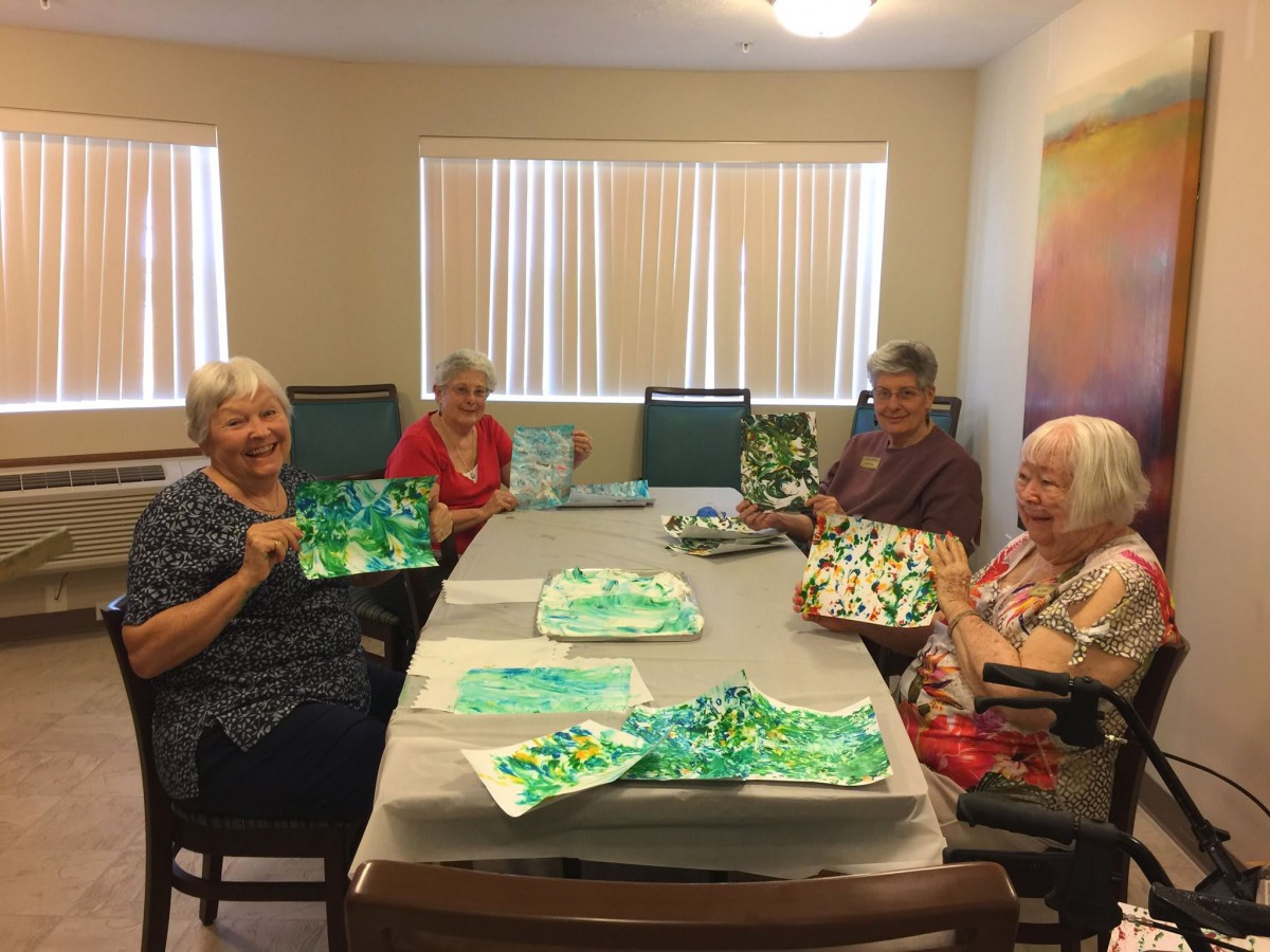 A group of seniors enjoying a painting session together at a table.
