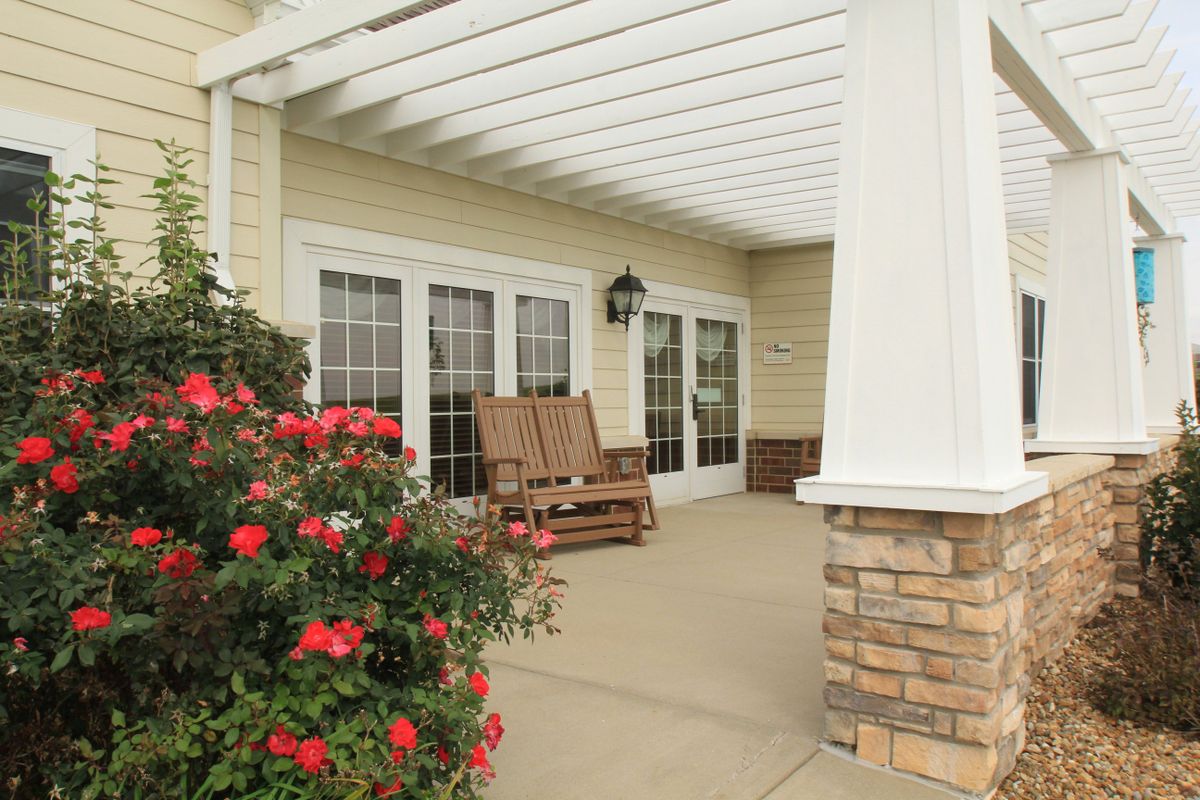 A cozy porch with wooden chairs and vibrant flowers, perfect for relaxation.