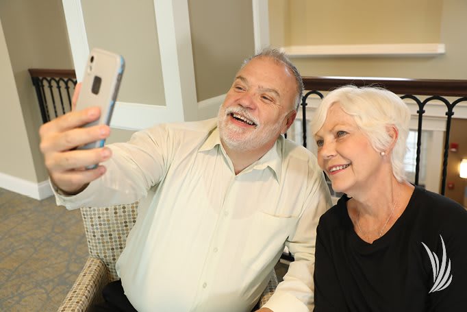 An older couple taking a selfie together indoors.