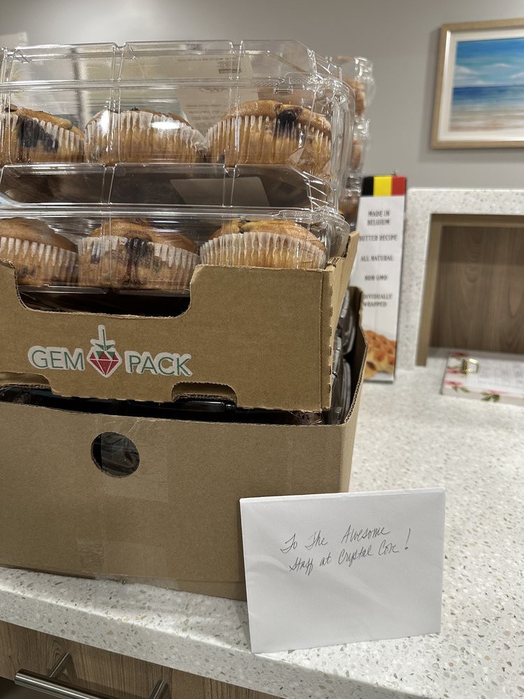 A stack of packaged muffins with a handwritten note in front.