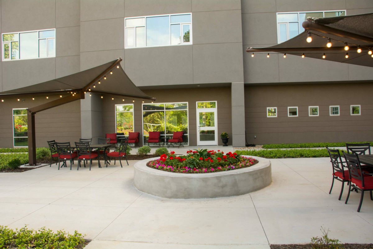 A modern outdoor patio with seating and string lights next to a building.