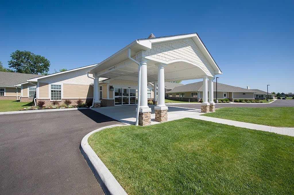 A building entrance with a covered canopy and surrounding landscaped lawn.