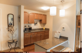A modern kitchen with wood cabinets, a microwave, and pendant lights.