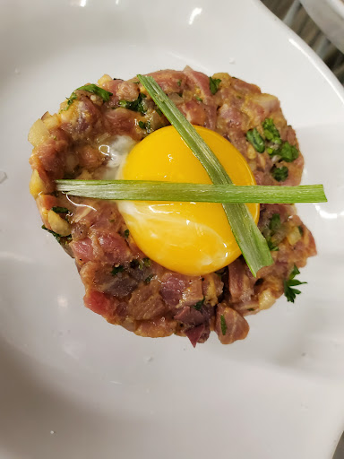 A beautifully presented dish of tartare topped with a fresh egg yolk and green onions.