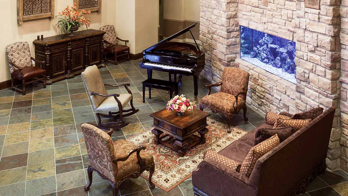 A cozy living room with a grand piano and comfortable seating around a coffee table.