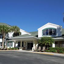 A residential building with palm trees and a welcoming entrance under a clear blue sky.