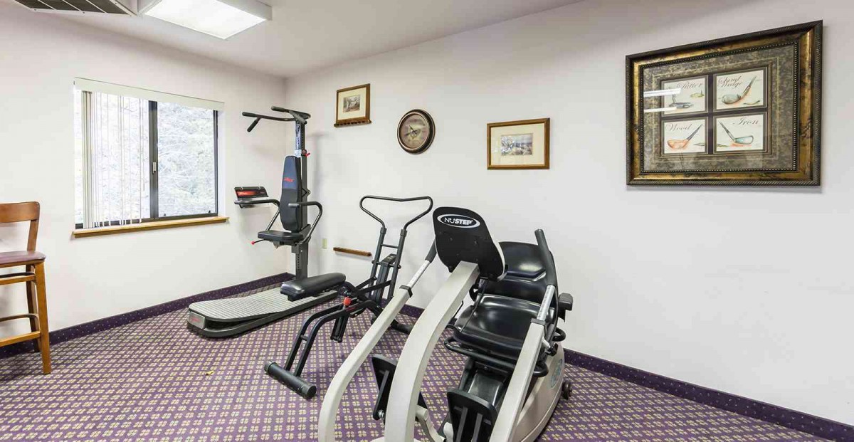 A small gym with various exercise equipment, including cardio machines.