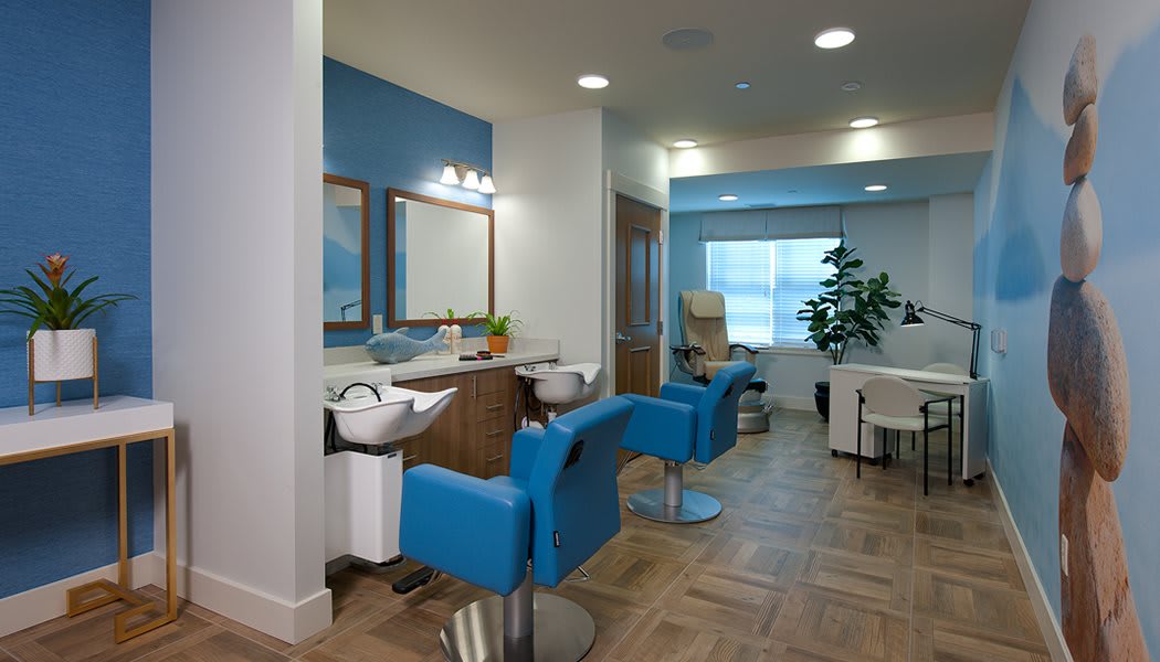 A modern hair salon interior with blue chairs and mirrors.