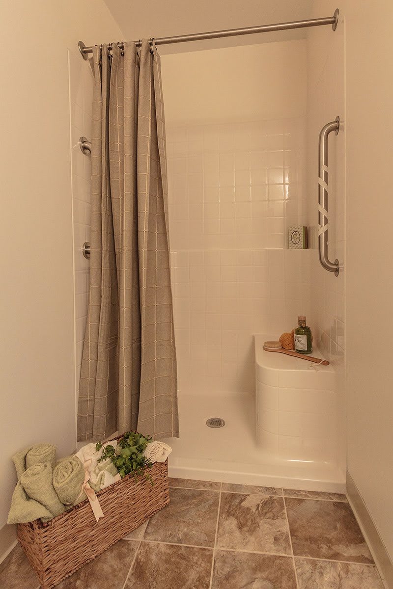 A cozy bathroom with a simple shower setup, featuring a curtain and neatly placed towels.