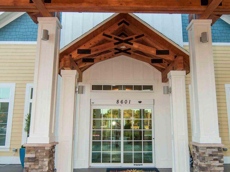 A building entrance featuring a wooden porch and glass doors.