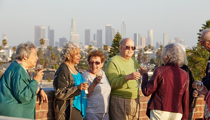 A group of seniors enjoying a drink with a city skyline in the background.