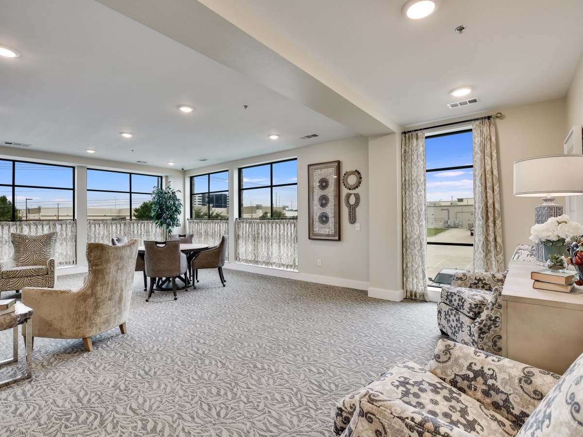 A spacious and elegantly designed living room with a dining area, featuring large windows that allow plenty of natural light.
