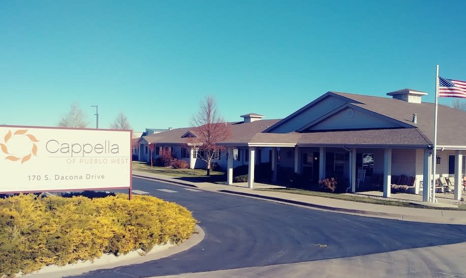 A sunny day view of a single-story building with a prominent entrance and landscaped surroundings.