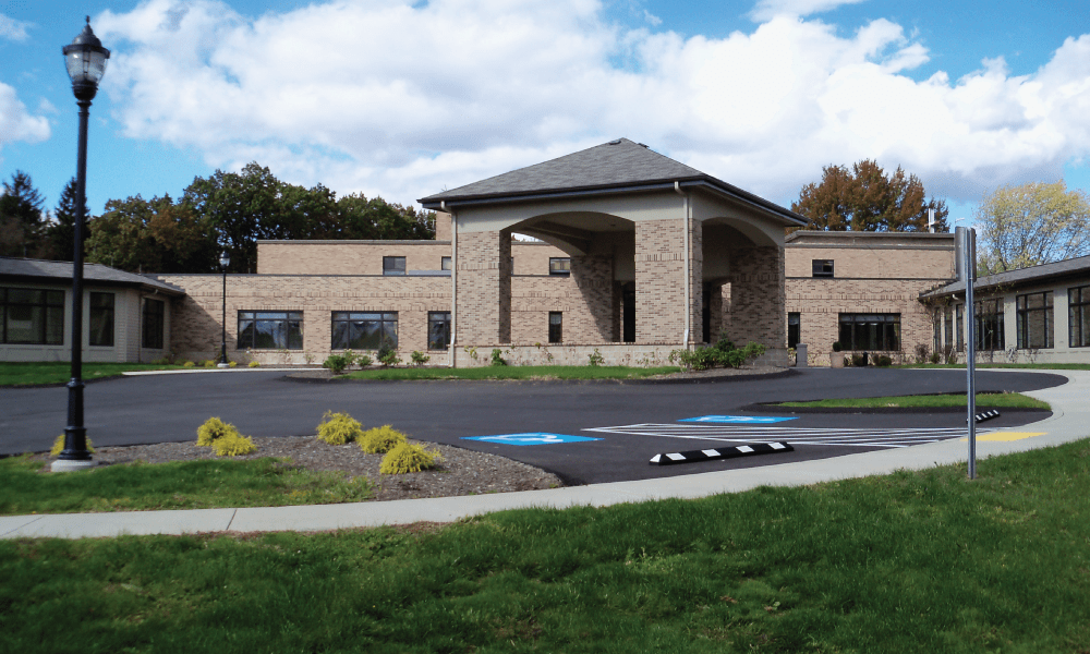 A modern building with a covered entrance and adjacent parking lot.