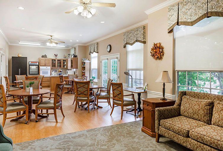 A spacious open-concept living and dining area with wood flooring, featuring a cozy seating arrangement and natural light streaming in from large windows.