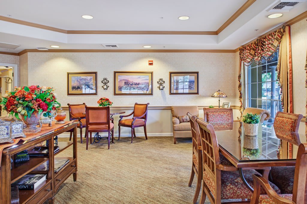 A cozy dining area with tables and chairs, decorated with framed art and warm lighting.