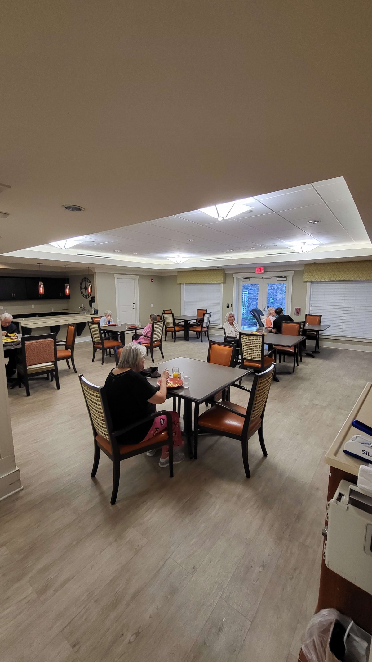 A cozy dining area with several tables and chairs, occupied by people enjoying their time.