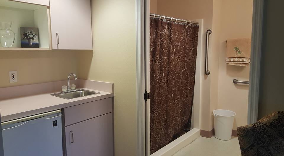 A bathroom with a sink, cabinet, and shower area with a curtain and handrail.
