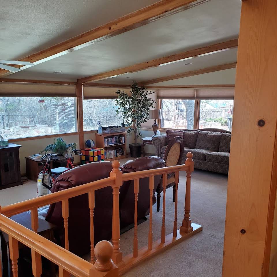 A cozy living room with wooden furniture and large windows letting in natural light.
