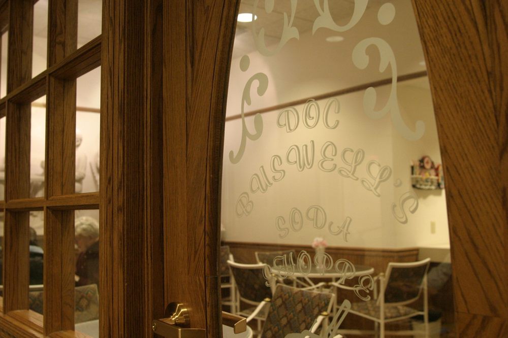 View through a wooden door into a cozy cafe with frosted glass decor.
