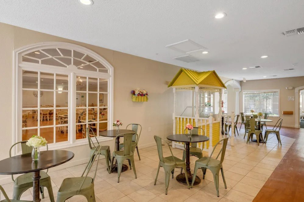 A modern indoor seating area with tables and chairs, featuring bright lighting and stylish decor.