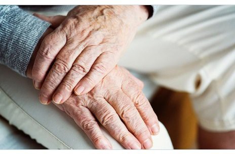 Close-up of elderly hands resting on a lap.