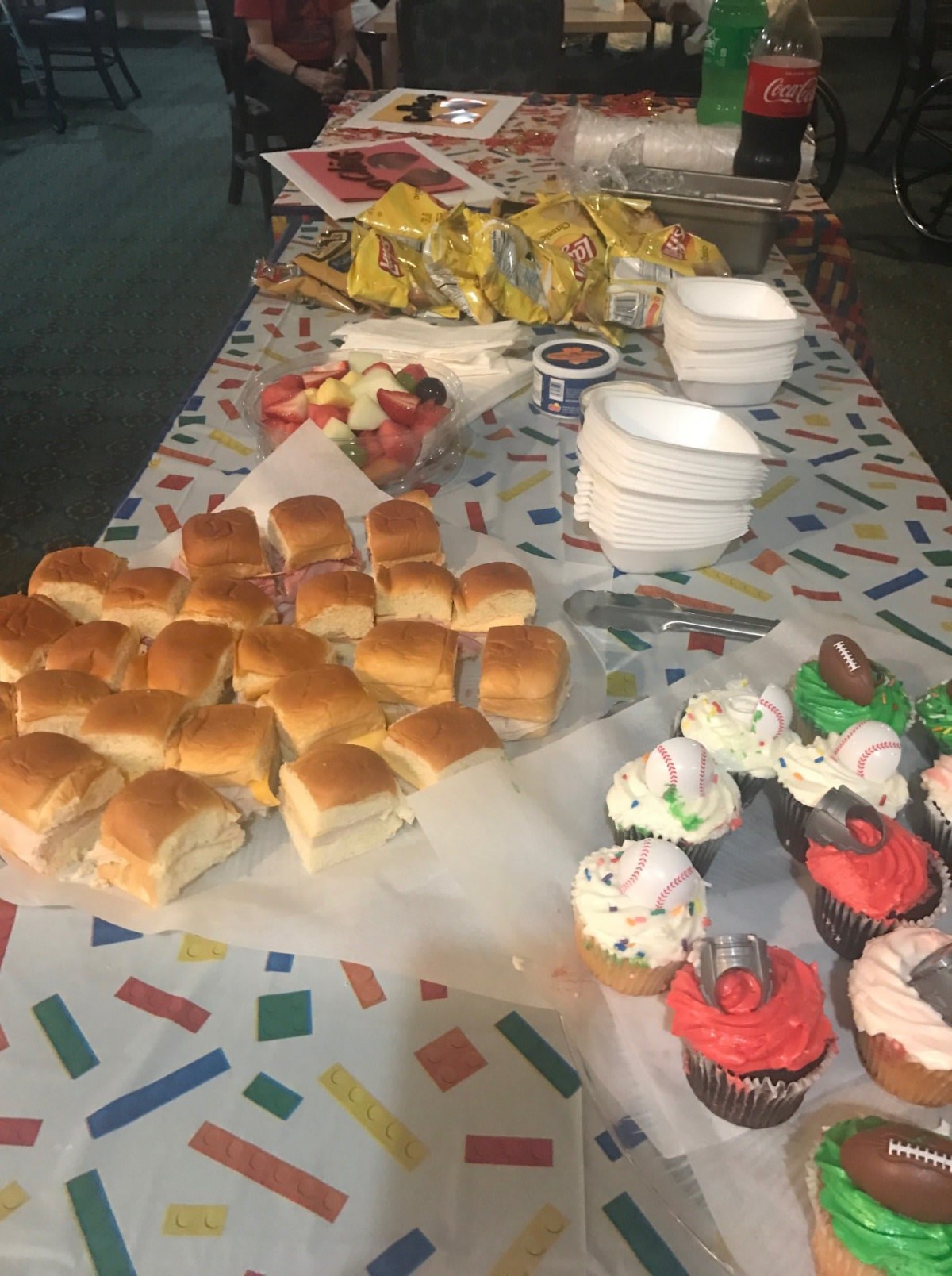 A party table set with sandwiches, cupcakes, and snacks.