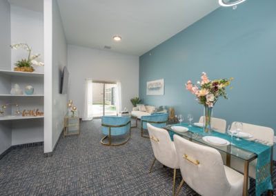 A modern living and dining area featuring a blue accent wall, contemporary furniture, and bright lighting.