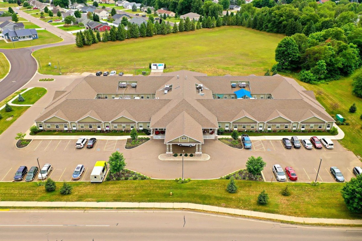 Aerial view of a large building with surrounding parking lot and greenery.