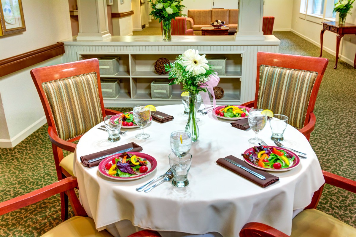 A beautifully set dining table with salads and a floral centerpiece in a restaurant.